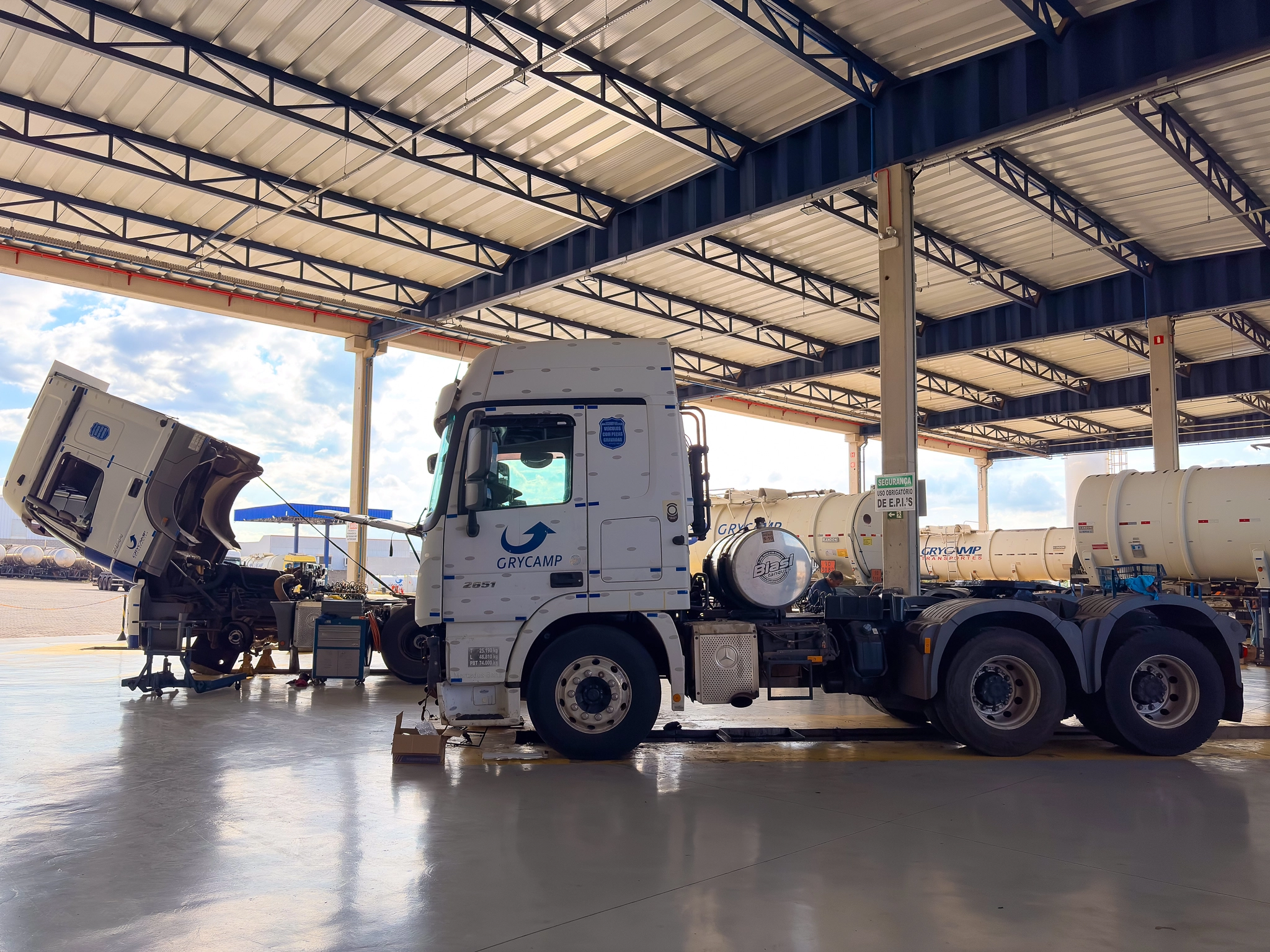 Caminhão Grycamp em manutenção dentro da oficina com cabine basculada