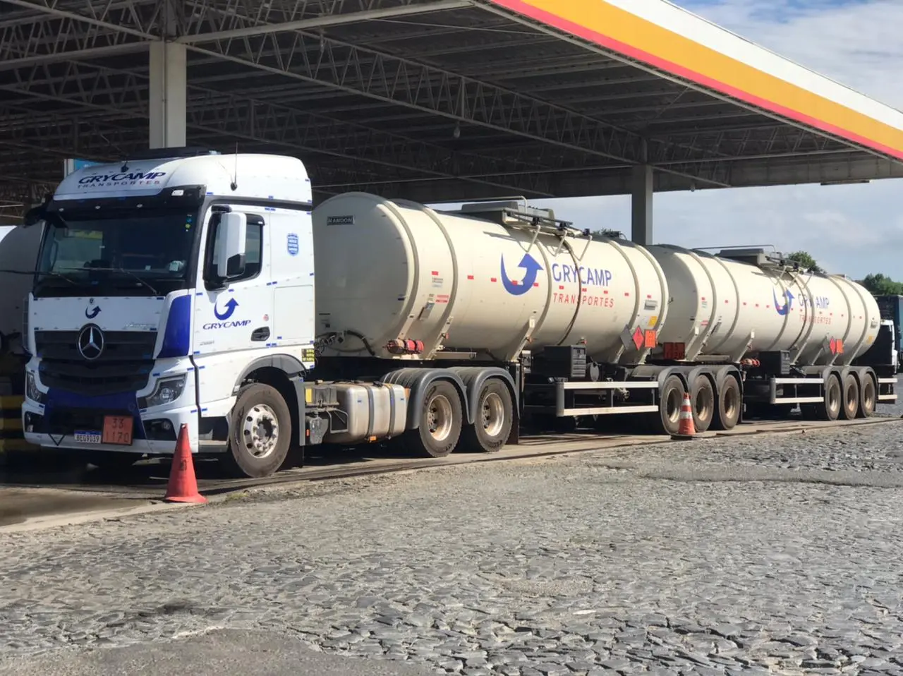 Caminhões-tanque Grycamp alinhados no pátio da base sob céu azul